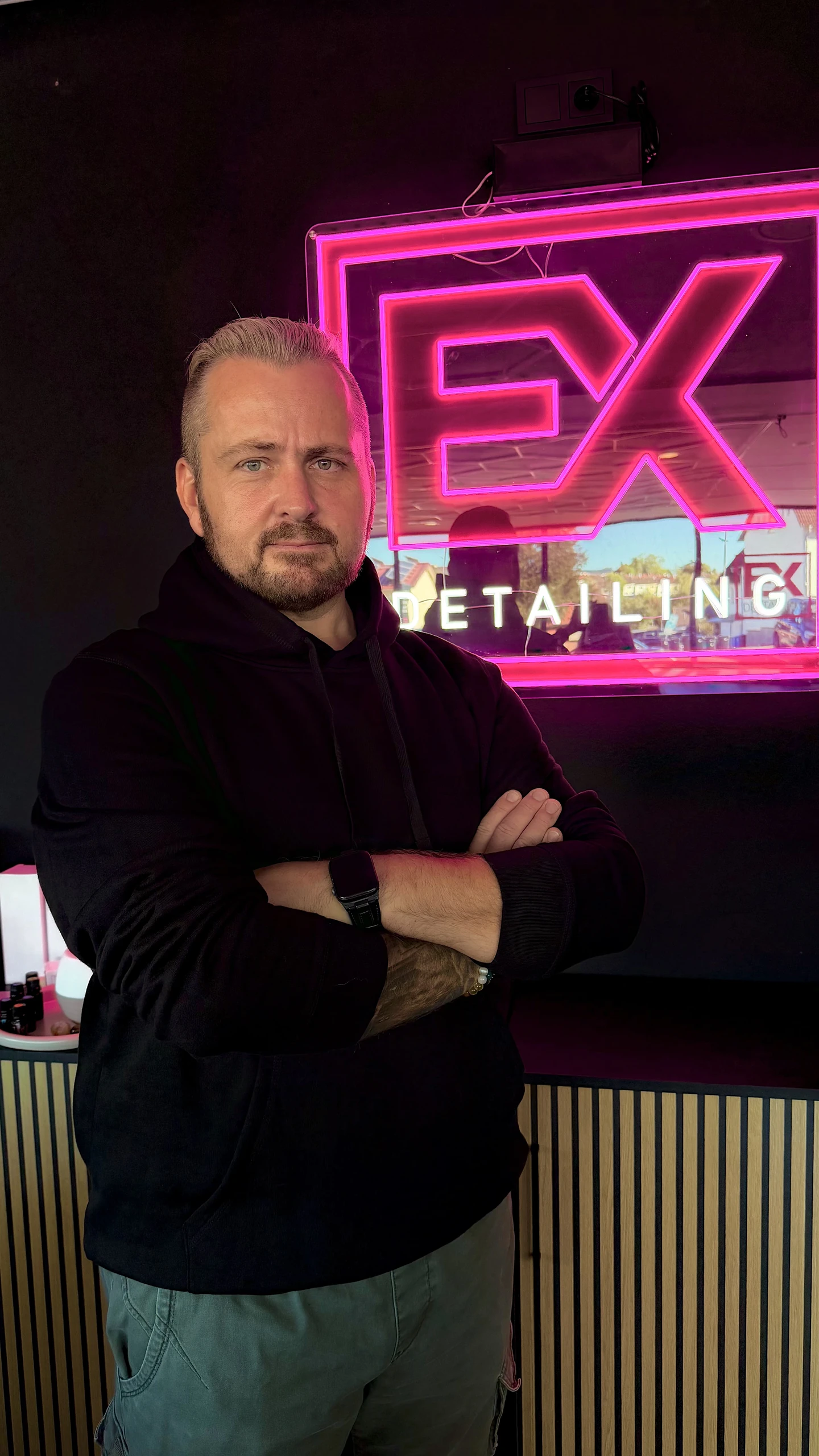 Eduard Koch vor dem beleuchteten EX-Detailing-Logo in seinem Studio