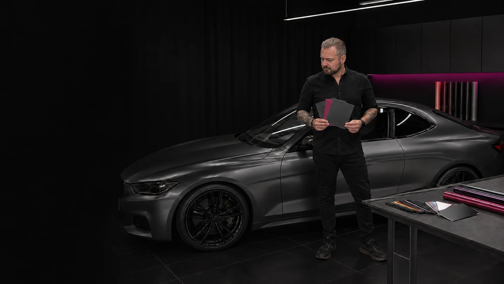 Eduard Koch vergleicht Folienmuster neben einem Fahrzeug im Studio